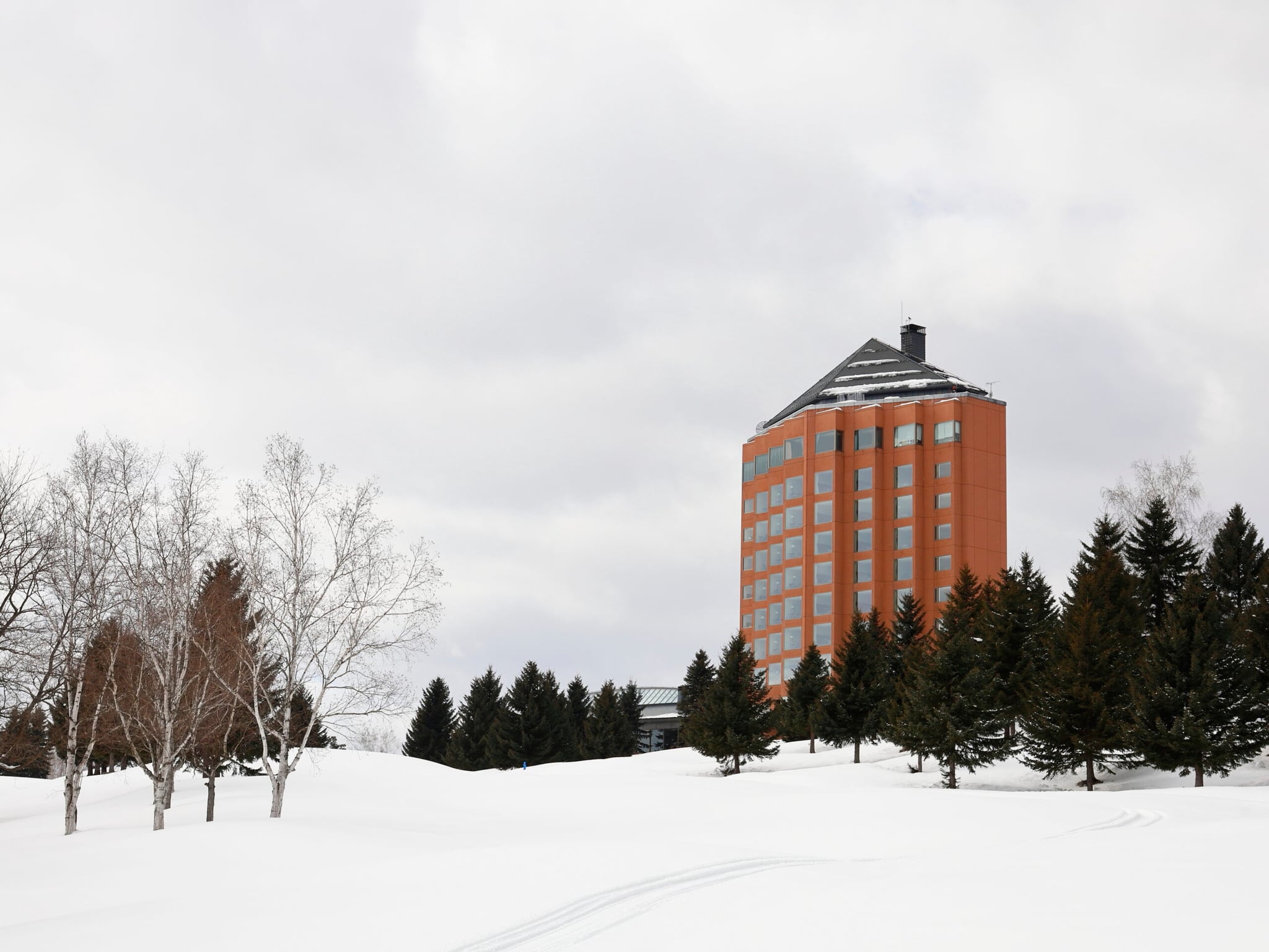 Furano Resort Orika’s orange hotel tower above evergreen trees and snow