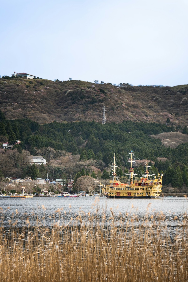 A yellow pirate ship sailing on Lake Ashi in Hakone with mountains in the background
