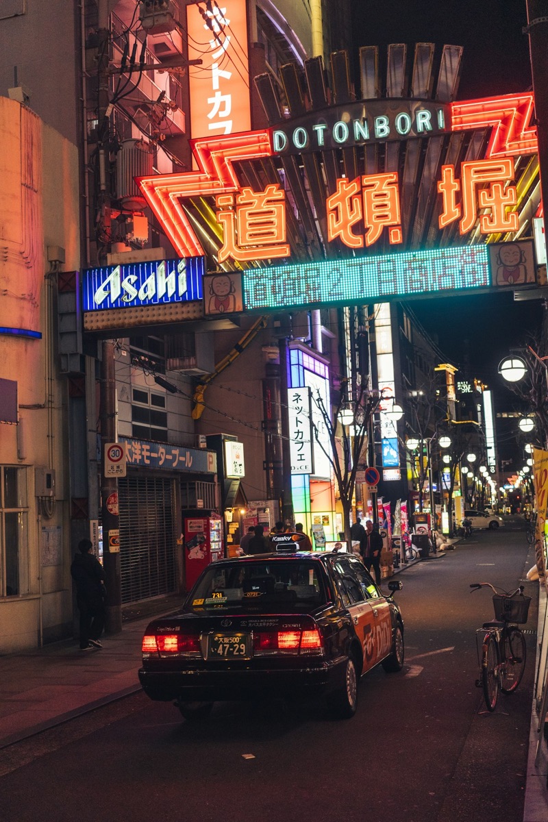 Neon signs illuminate a street in Dotonbori, Osaka at night