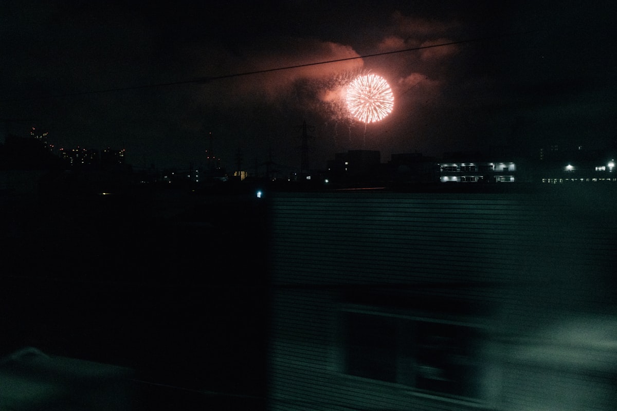 Fireworks exploding over a dark city skyline at night during a Japanese summer festival
