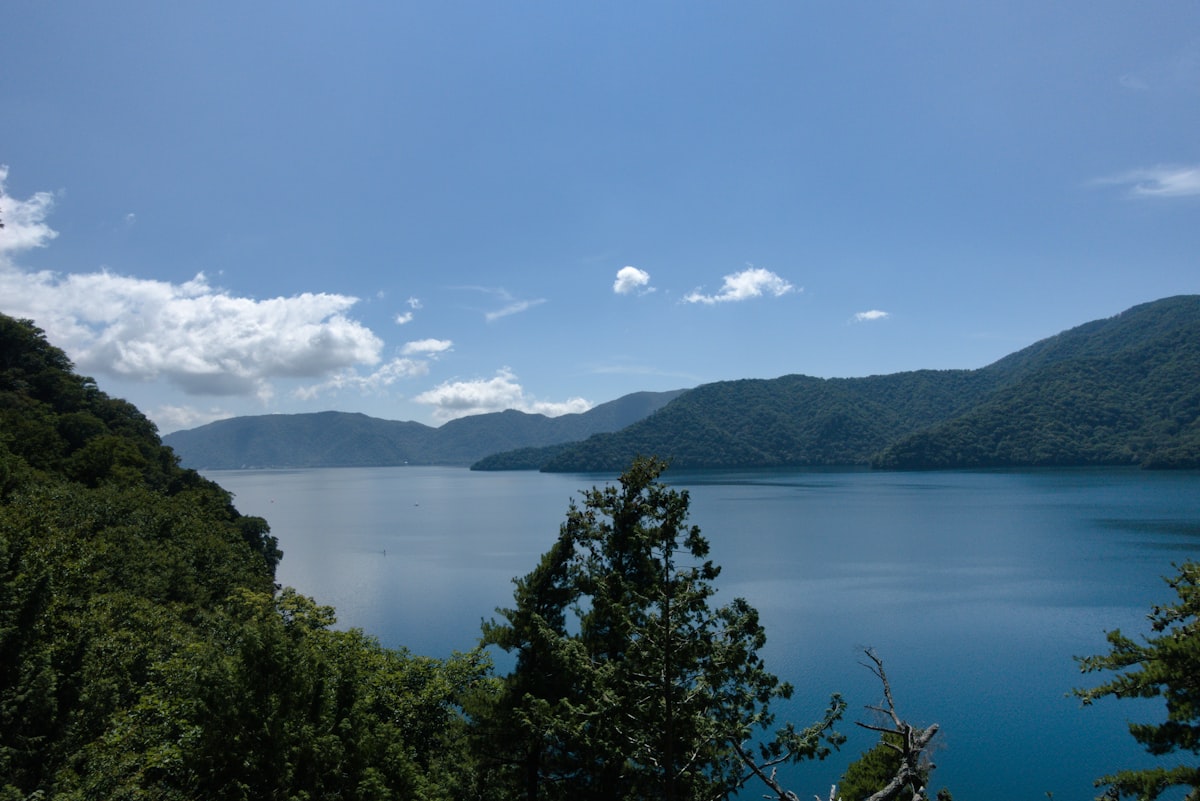 A serene blue lake surrounded by lush green mountains in northern Japan
