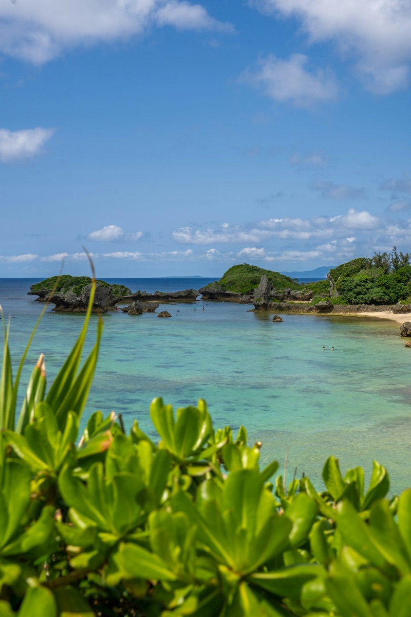 A turquoise ocean cove and sandy beach in Okinawa under a clear summer sky