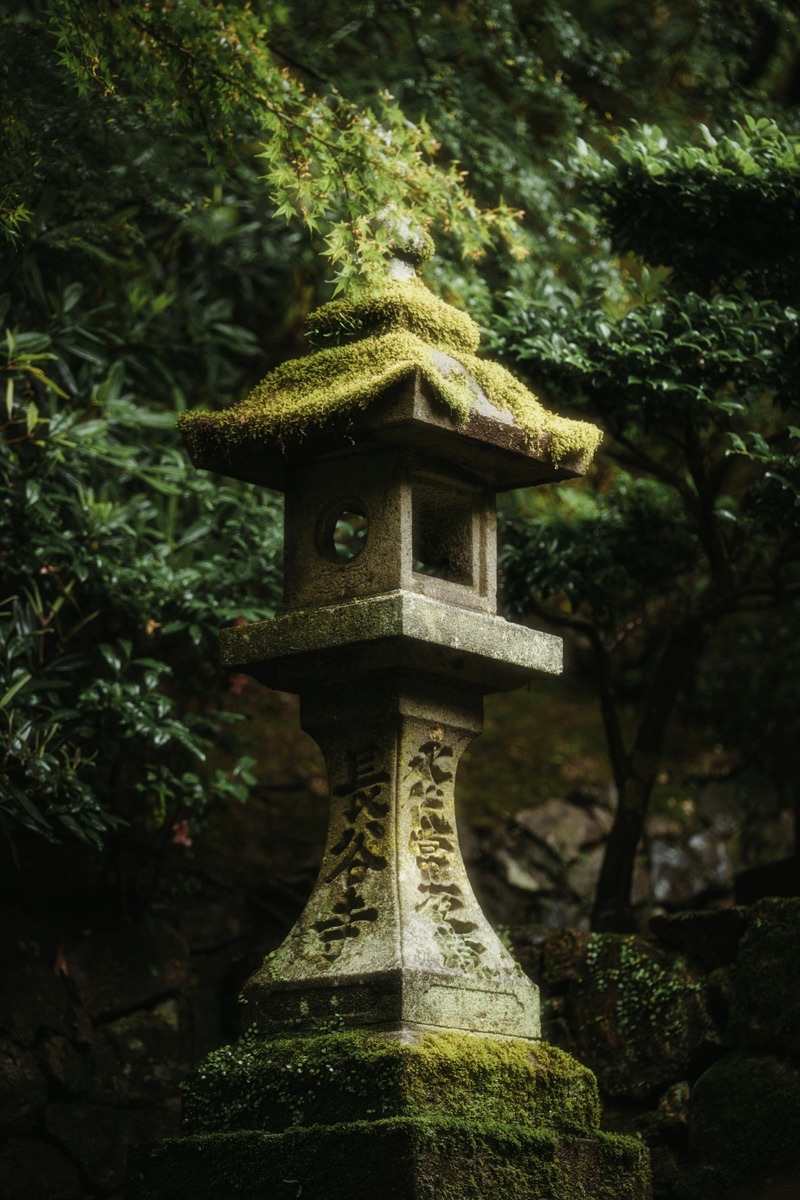 A mossy Japanese stone lantern in a traditional Japanese garden, glowing emerald after rainfall