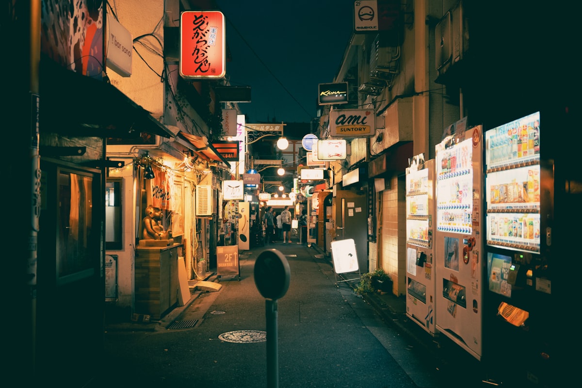 A narrow Tokyo alleyway with shops and neon signs in the evening