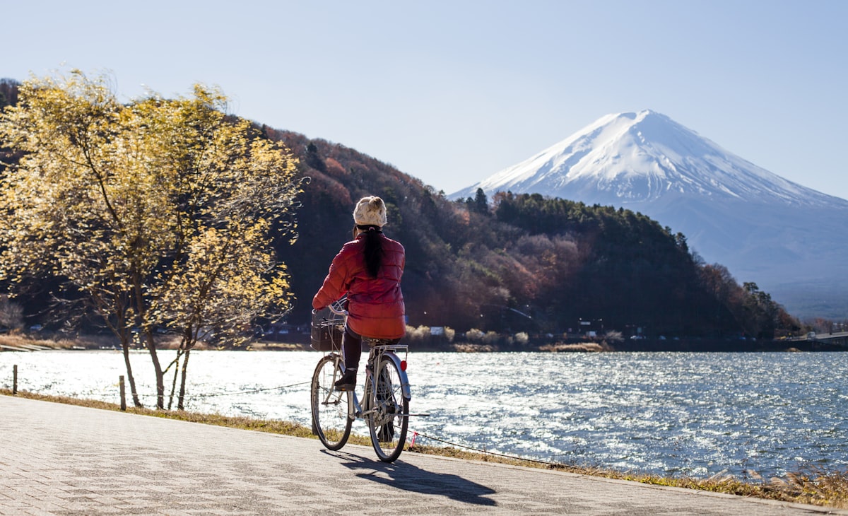 A cyclist riding along Lake Kawaguchi with Mount Fuji visible in the distance