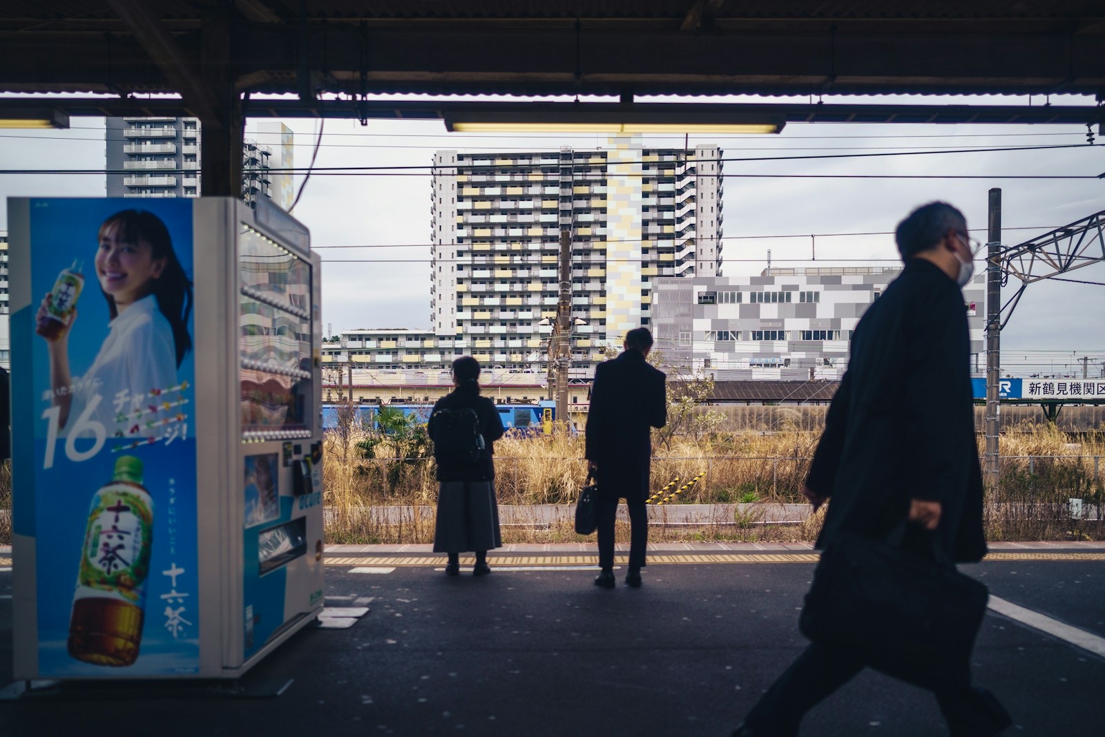 A Japanese station platform with commuters waiting for a local train
