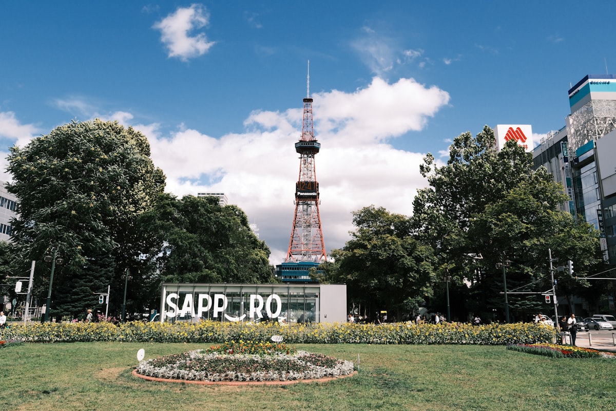 Sapporo TV Tower in Hokkaido under clear summer skies, with green trees in Odori Park