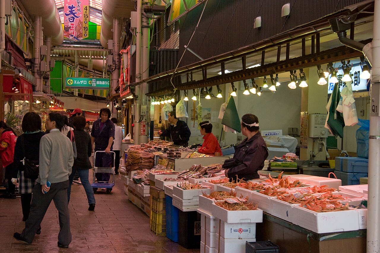 Seafood sellers and shoppers beside boxes of crab in the covered aisles of Omicho Market