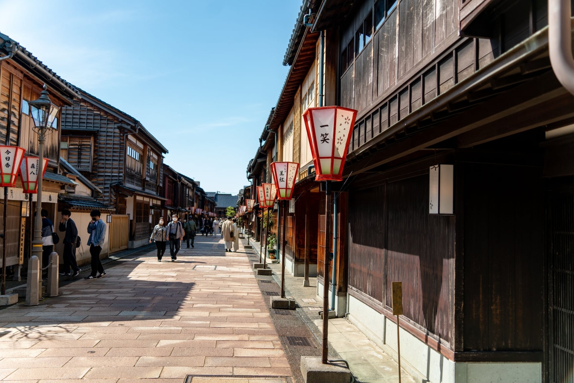 Traditional wooden teahouses and red lanterns along a paved street in Higashi Chaya