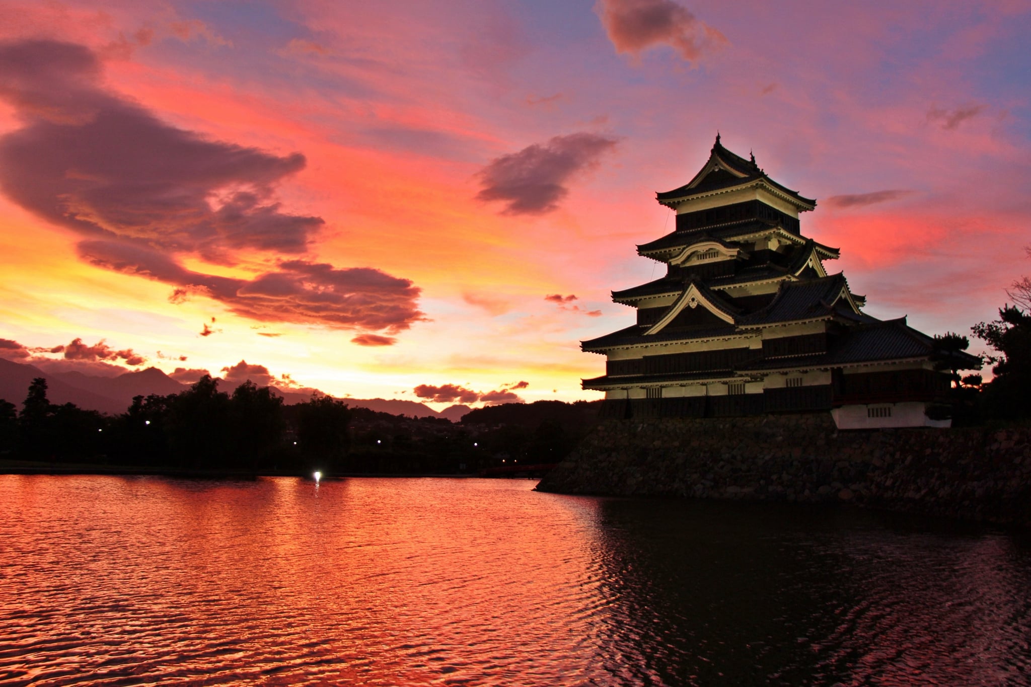 Matsumoto Castle reflected in its moat beneath a sunset sky